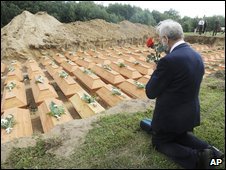 A man prays in front of coffins during the reburial ceremony in the village of Stare Czarnowo, Poland, 14 August 2009 