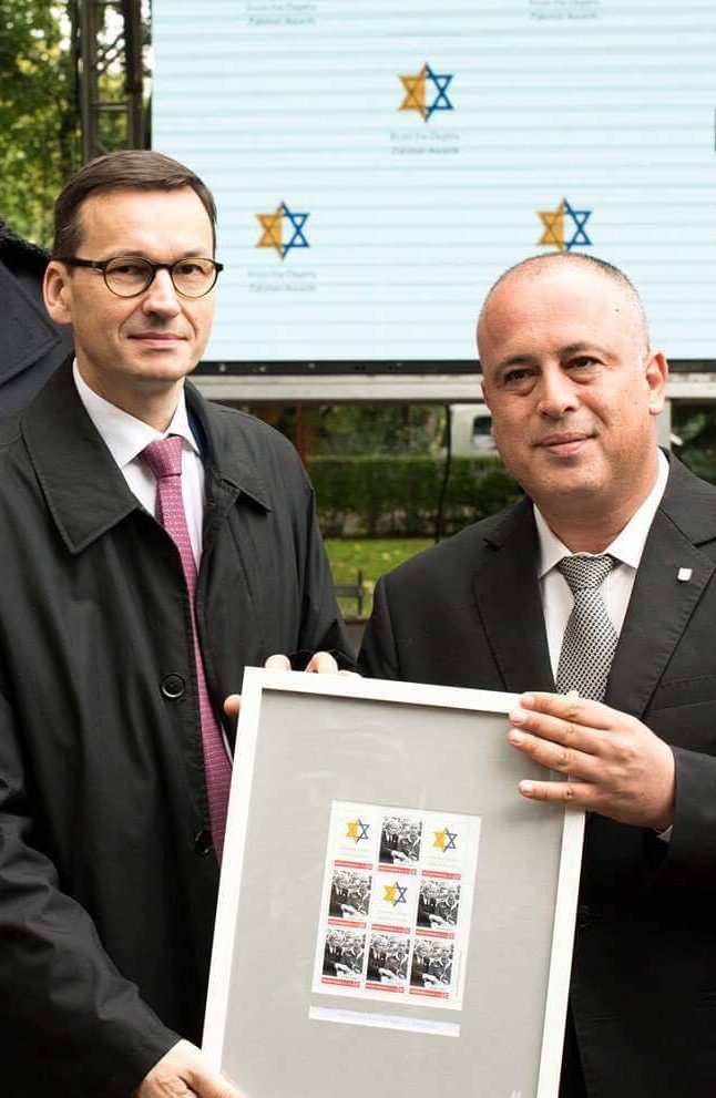 Mateusz Morawiecki holds a document honoring rescuers of Polish Jewry
