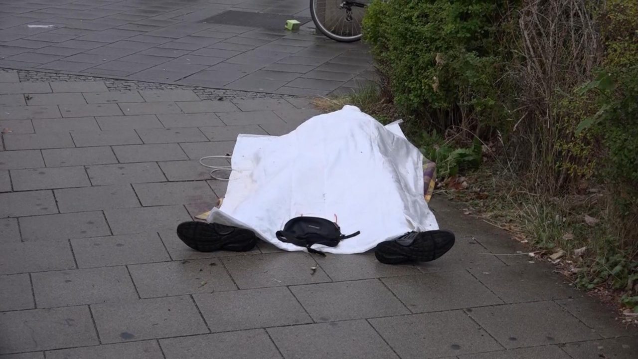 A body covered with a sheet lies on the sidewalk ouside the Olympic Mall in Munich