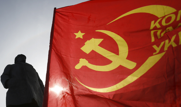 A man waves a communist flag in front of a monument to Soviet Union founder Vladimir Lenin.