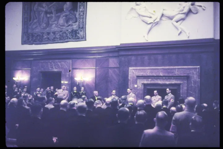 Joseph Goebbels and Adolf Hitler at left of fireplace, Rudolf Hess on far right hold a press conference at the Führerbau in Munich, Nov. 11, 1938.